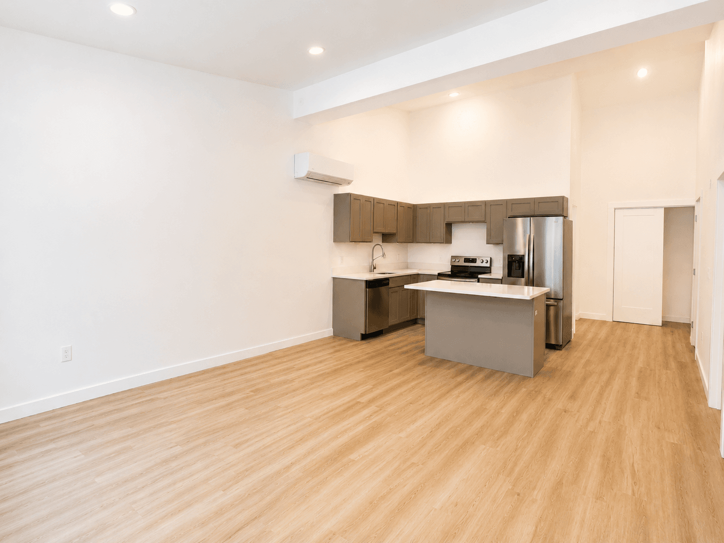 Wide view of a Tillson Woods kitchen and open living area with coordinated refrigerator placement.